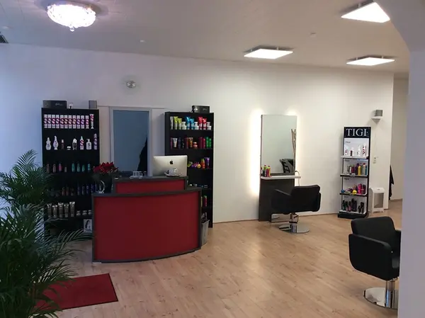 Moderner Friseursalon mit Empfangstresen, Regalen voller Haarpflegeprodukte und Stylingbereich.
