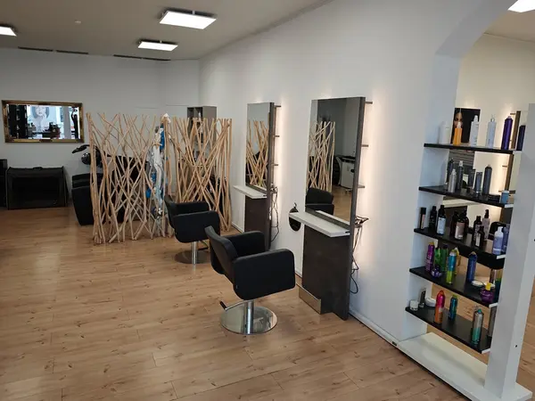 Moderner Friseursalon mit zwei Frisierplätzen, Spiegeln und Regalen voller Haarpflegeprodukte.